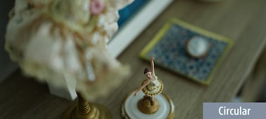 Example image showing a small ballerina figurine in focus on a wooden table with background bokeh