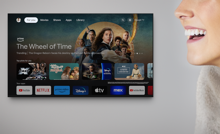 Wall-mounted television showing a variety of entertainment apps and selected shows with woman's head to the right