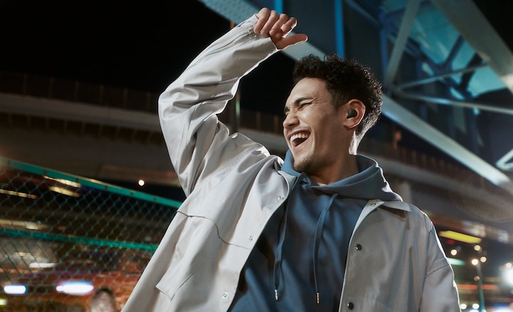 Split-screen image of a man dancing in a stadium environment wearing LinkBuds S with Ambient Sound Mode on and arm raised