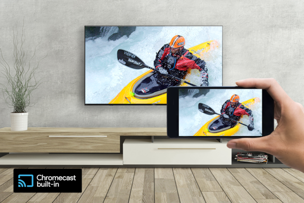 A hand holds a smartphone in front of a wall-mounted TV—both screens display the same kayaking image. A logo for Chromecast built-in sits on the bottom left.