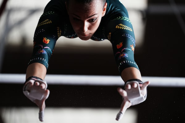 Example image of a female gymnast in mid-swing between uneven bars, arms outstretched